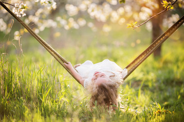 Child girl is having fun in hammock outdoors