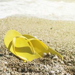 Pair of yellow flip flops on a beach