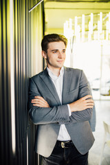 Successful businessman dressed in expensive suit is standing in hallway his company. Young male manager is posing in modern office