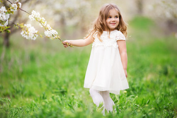 Fototapeta na wymiar Pretty child girl in blossom spring garden