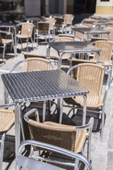 Empty cafe on the terrace on a summer day, without guests, white chairs and tables, selective focus