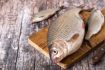 
River fish.   Fresh river fish roach, large and small, on a cutting board on an old wooden table.