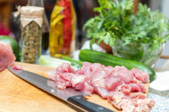 Raw pork neck meat cut in slices on wooden cutting board  in a modern kitchen. Shallow depth of field. Toned