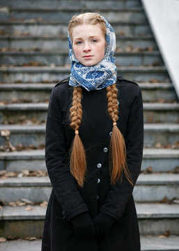 Emotional portrait of happy beautiful woman with red braids hair and natural makeup wearing black jeans trench grey sweater blue white headcraft enjoying her life in spring city park.
