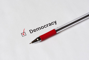 Questionnaire. Red pen and the inscription Democracy with check mark on the white paper
