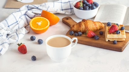 Breakfast with croissant, berries and book on white background