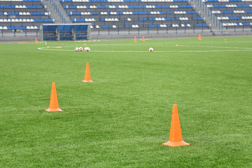 Cones and balls for football training at the stadium. Sports background. Artificial lawn on a soccer field.