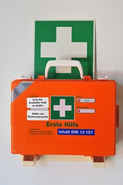 Erste-Hilfe-Koffer in Wandhalterung mit Rettungszeichen f&uuml;r Erste Hilfe