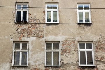 Fototapeta na wymiar Six windows on the facade of the ragged old house