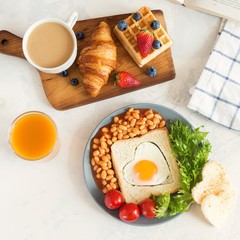 English breakfast: fried egg, beans and toast on a plate with tomatoes cherry, salad, juice, berries and croissant