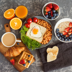 English breakfast: fried egg, beans and toast on a plate with tomatoes cherry, salad, juice, berries and croissant
