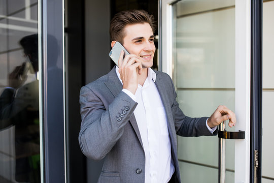 Young Business Man Speak On His Phone Near A Glass Door In Office Building