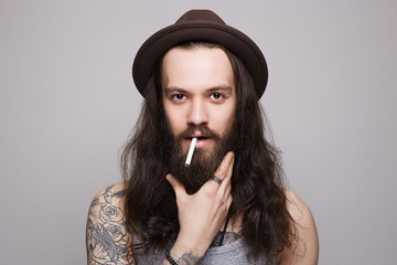 handsome bearded man in the hat smoking a cigarette