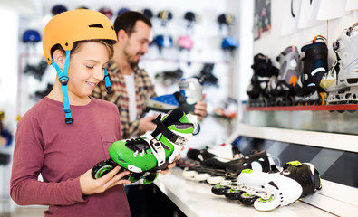 Seller assisting boy in choosing roller-skates