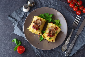 Pasta rolls with vegetables: paprika, onion, olives, mushrooms, tomato on a light brown plate on a grey abstract background. Vegetarian food. Dieting. Mediterranean lifestyle