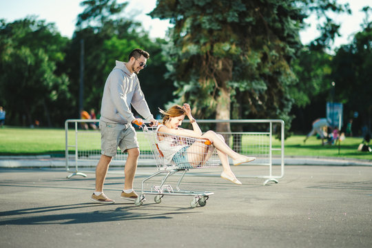 Happy love couple having fun 
with a supermarket trolley