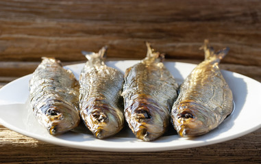 Geräucherter Fisch / Bücklinge auf Teller mit Holz / Treibholz Hintergrund, Textfreiraum