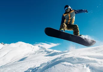 Gordijnen snowboarder is jumping with snowboard from snowhill © Аrtranq