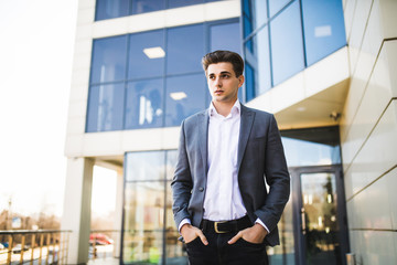 Elegant handsome young businessman while walking in front of office building