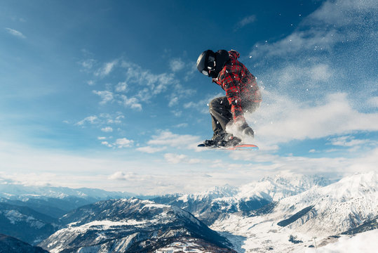 snowboarder is jumping with snowboard from snow mountain
