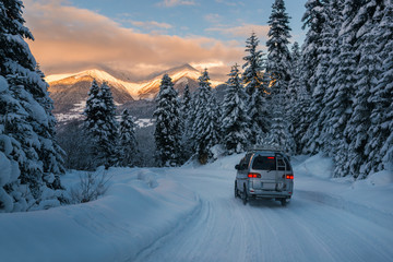 the car is riding on the powder snow road in the mountains