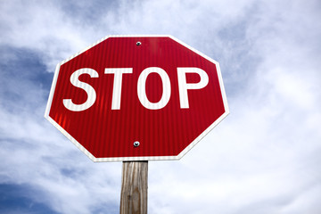 Looking up at new stop sign against blue sky with wispy clouds