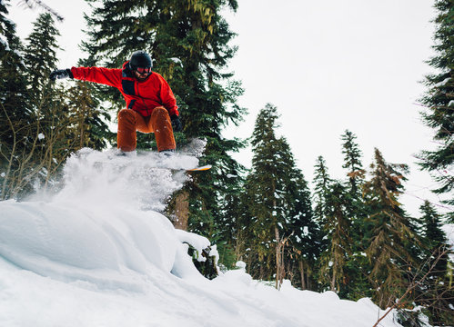 snowboarder in red suit is riding in the mountain forest