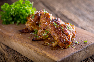 Chicken wings grilled BBQ  parsley herb and sesame on wooden board.