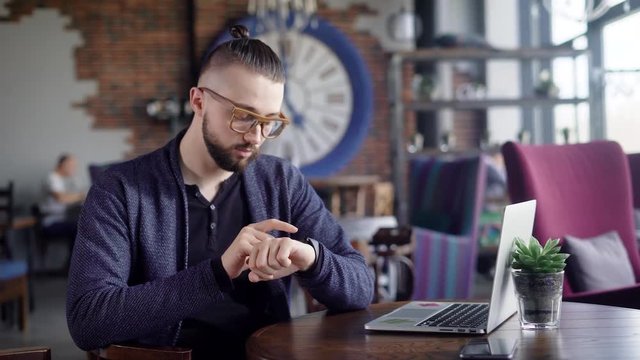 Smartwatch on a mans hand. Hipster sits in a cafe and uses his smart watch, he can view the messages, activate the applications, adjust the ezhelnevnik.