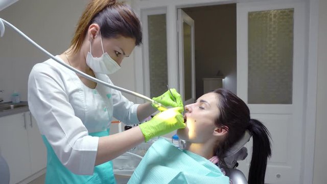Woman at the dental hygienist getting professional tooth cleaning and whitening. Shot in 4k