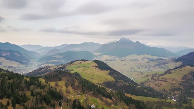 Aerial view of beautiful rural nature in early spring with clouds moving over mountains, time lapse