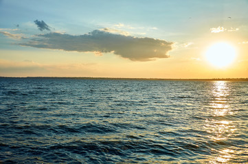Beautiful sea, river, lake, reservoir. Natural panorama in the rays of the setting, the rising sun. A magnificent blue sky with neat clouds. 