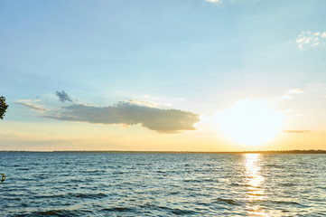 Beautiful sea, river, lake, reservoir. Natural panorama in the rays of the setting, the rising sun. A magnificent blue sky with neat clouds. 