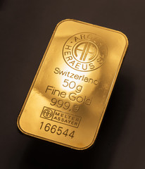 Minted gold bar weighing 50 grams against a dark background.
