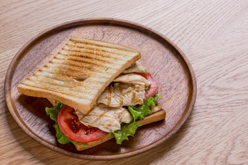 Sandwich with chicken on wooden plate, flat lay top view.