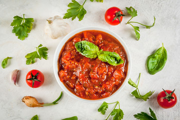 Basic Italian tomato sauce marinara for pasta. In a saucepot with ingredients on a white concrete table. Top view - obrazy, fototapety, plakaty