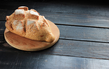 Fresh bread with cutting board on a dark wooden table