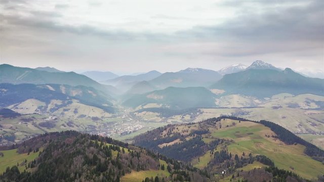 Aerial view of beautiful rural nature in early spring with clouds moving over mountains, time lapse