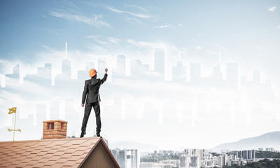 Man architect draw silhouette of modern city on blue sky. Mixed 