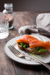 Sandwich with cream cheese, salad leaves and salted salmon on rustic background
