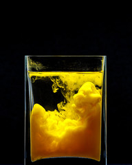 Yellow Paint swirling in water on black background. Splashes of paint in a glass jar. Flat style