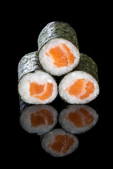 Sushi maki with salmon, on a black background with reflection. Asian food