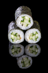 Sushi maki with cucumber, on a black background with reflection. Asian food