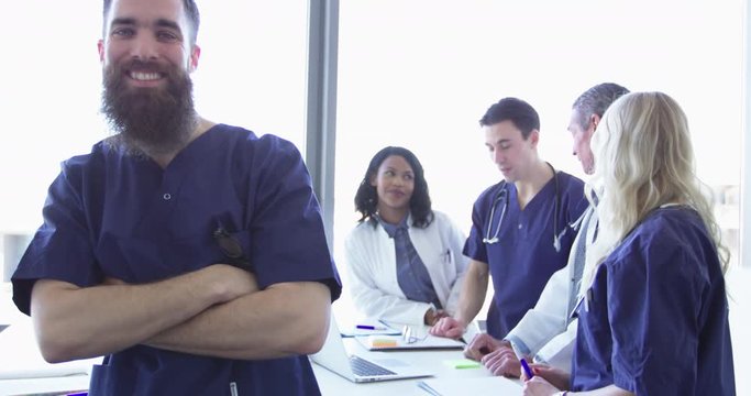 Confident relaxed surgeon doctor at hospital with team of doctors in background