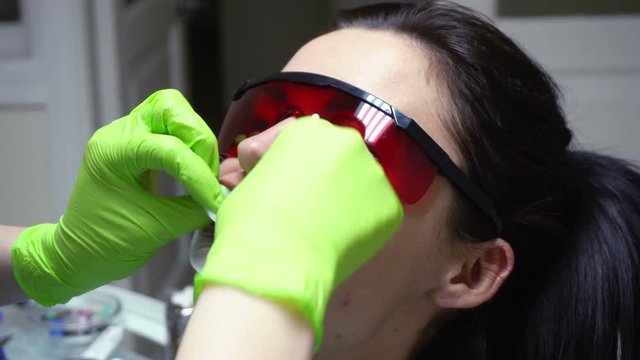 Closeup view of the dentist's hands putting rubber dam in a mouth of a female patient. Shot in 4k