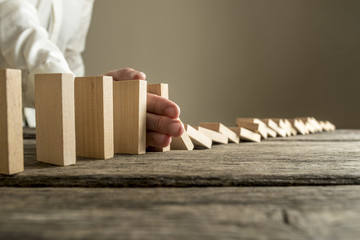 Man in white shirt stopping domino effect