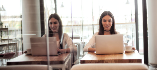 Smiling young woman drinking a coffee and surfing on internet