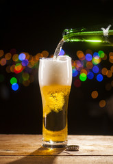 Beer is pouring into glass on bar lights background