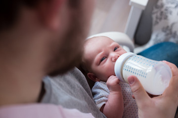 Young father feeding his newborn daughter. Lifestyle image, natural light.