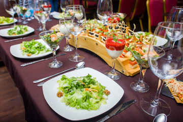 the table is laid for celebration,  there are glasses and salad and snack